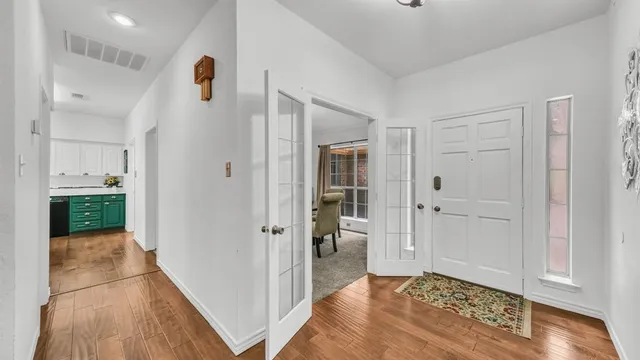 a view of a hallway with wooden floor and a bathroom