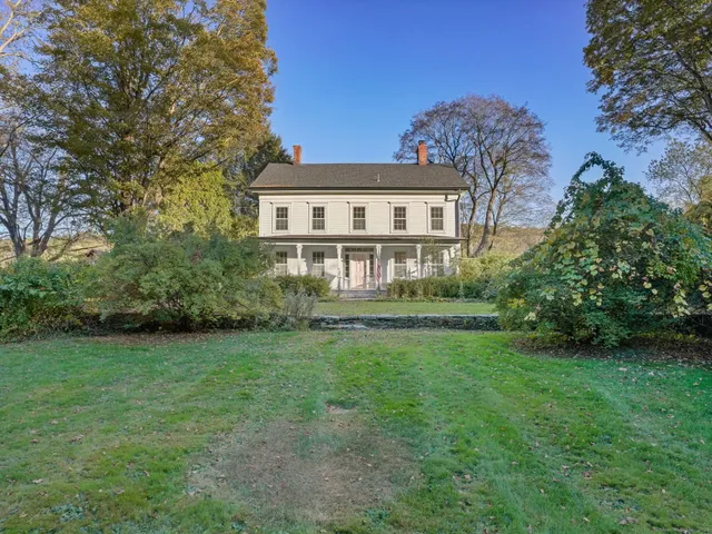 a view of a house with a big yard plants and large trees