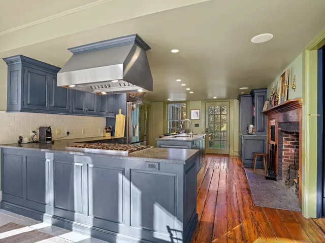 a kitchen with stainless steel appliances granite countertop a refrigerator a sink dishwasher a stove and a dining table with wooden floor