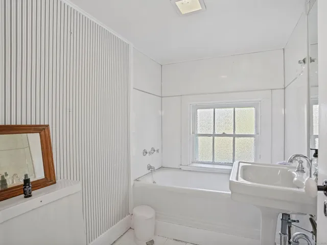 a bathroom with a bathtub a sink a toilet and a window
