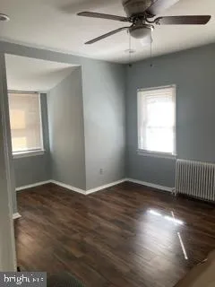 an empty room with wooden floor fan and windows