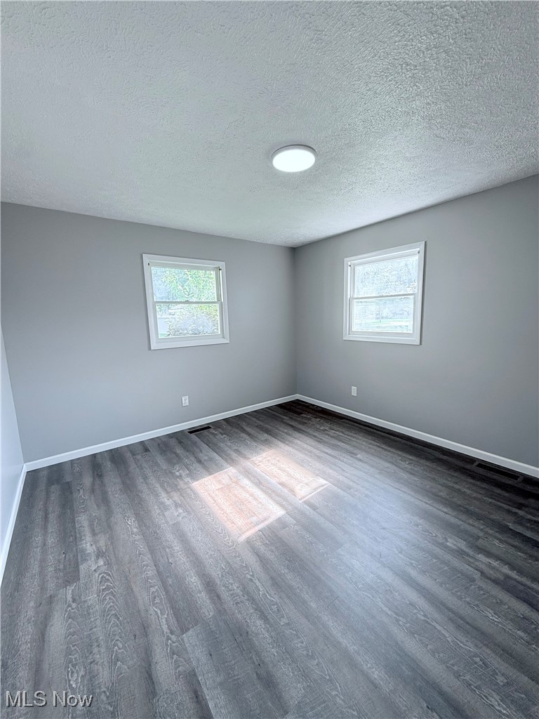 4816 Wake Robin Road Mentor, OH 44060 - Photo 17 of 19 Empty room with dark wood-style flooring, healthy amount of natural light, a textured ceiling, and baseboards