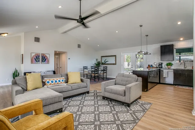 a living room with furniture kitchen view and a wooden floor
