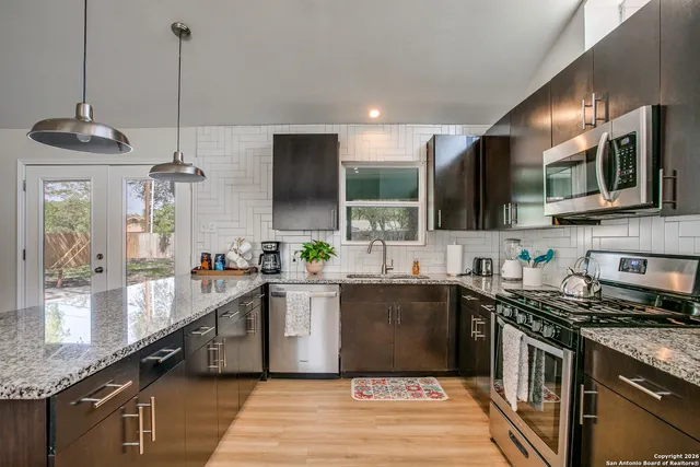 a kitchen with stainless steel appliances granite countertop a sink a stove and a wooden floors