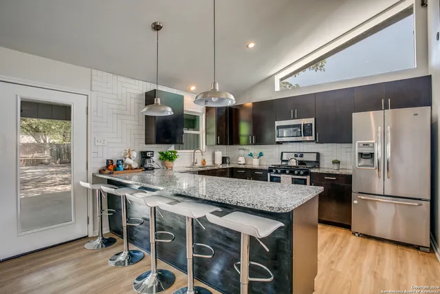 a kitchen with a center island wooden floor and stainless steel appliances