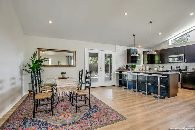 a kitchen with stainless steel appliances kitchen island granite countertop a table chairs sink and cabinets