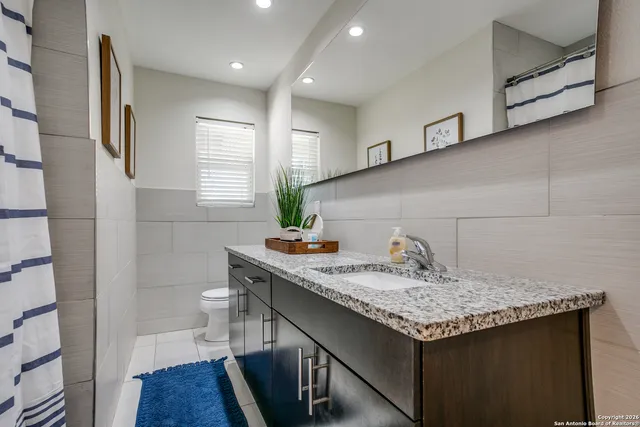 a bathroom with a granite countertop sink a toilet and a mirror