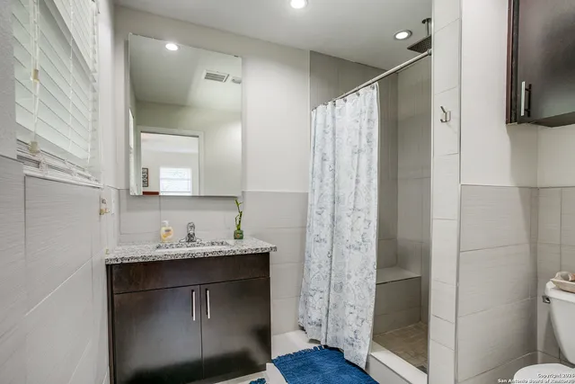 a bathroom with a sink a toilet a mirror and shower