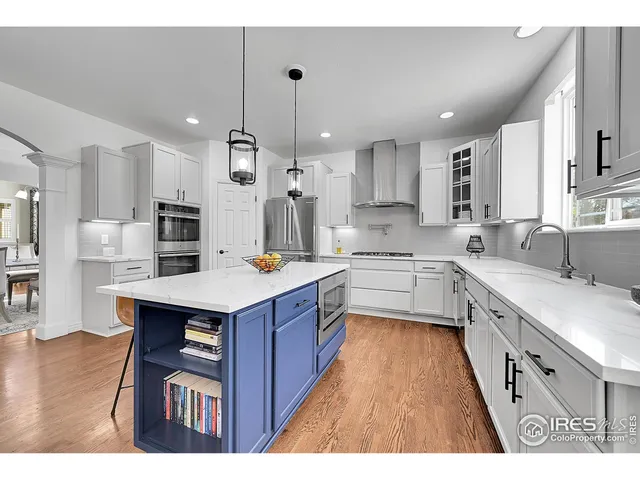 a kitchen with stainless steel appliances kitchen island a large counter space a sink and a wooden floors