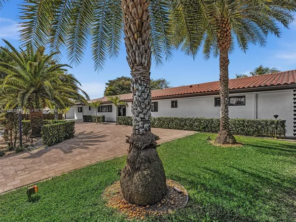a front view of a house with a yard and palm trees