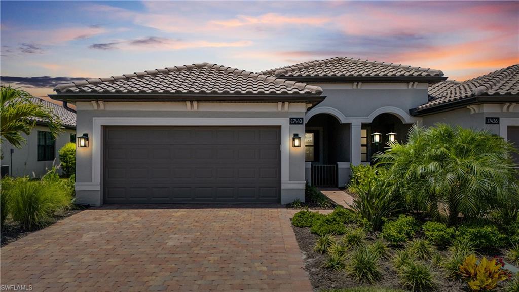 Mediterranean / spanish-style home featuring decorative driveway, a tile roof, stucco siding, and an attached garage