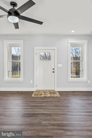 a view of an empty room with a window and wooden floor