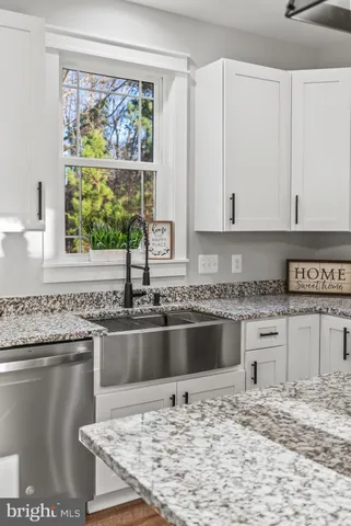 a kitchen with granite countertop a sink and white cabinets