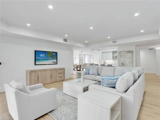 a living room with couches and kitchen view with wooden floor