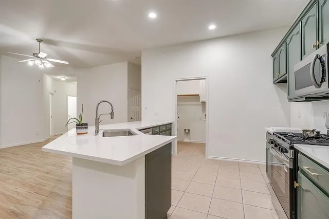 a kitchen with stainless steel appliances a sink a stove a refrigerator cabinets and a dining table