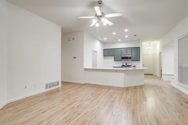a large kitchen with kitchen island a island wooden floors a white counter and a sink