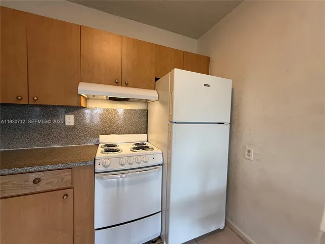 a white refrigerator freezer and a stove sitting inside of a kitchen
