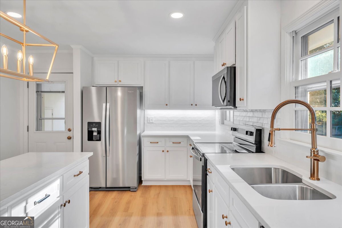 1806 Knox Street Dublin, GA 31021 - Photo 16 of 49 a kitchen with a refrigerator sink and white cabinets with wooden floor