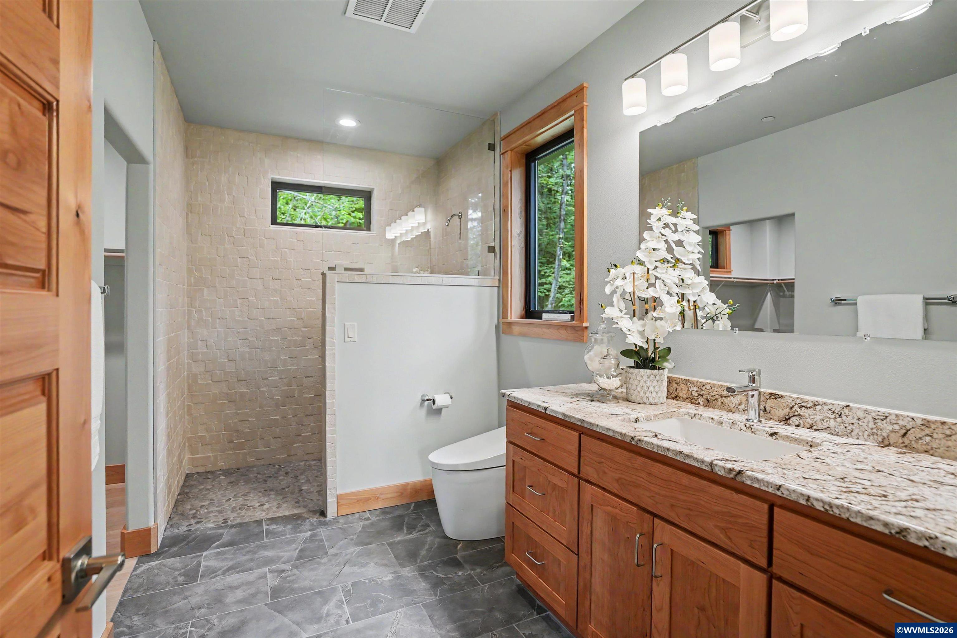 1155 Northwest Country Hills Road Corvallis, OR 97330 - Photo 44 of 48 a bathroom with a granite countertop sink a toilet a mirror and shower