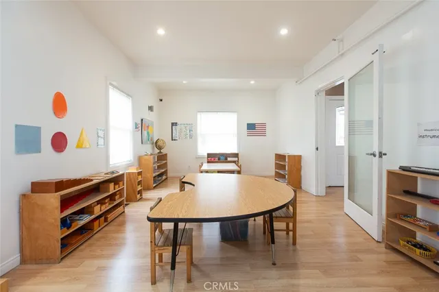 a living room with dining table and a refrigerator
