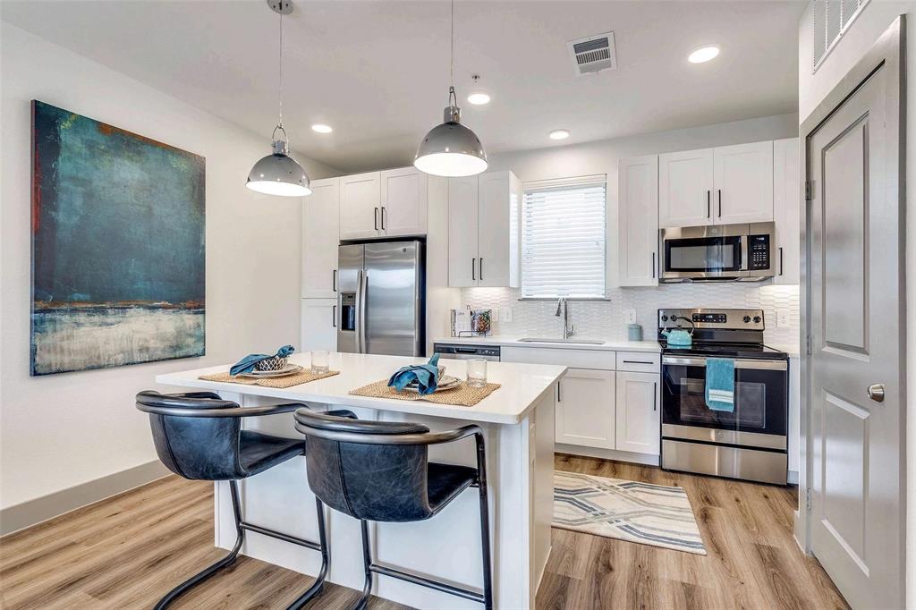 4020 McEwen Road, Unit 9123 Farmers Branch, TX 75244 - Photo 1 of 20 Kitchen with stainless steel appliances, decorative backsplash, white cabinetry, light wood-style floors, and recessed lighting