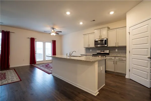 a open kitchen with stainless steel appliances granite countertop a stove top oven a sink dishwasher and a microwave with wooden floor