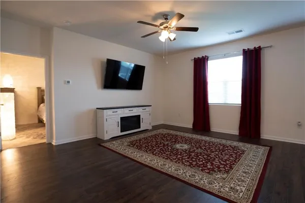 a view of an empty room with window and wooden floor