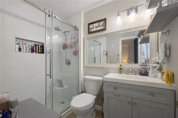 a bathroom with a sink a toilet a large mirror and shower