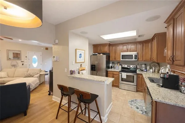 a large kitchen with a table chairs wooden cabinets and stainless steel appliances