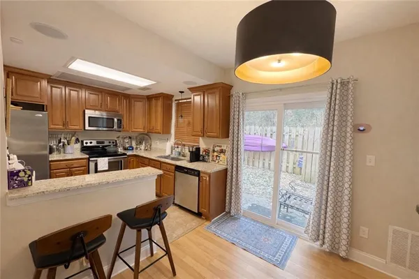 a kitchen with stainless steel appliances a stove a refrigerator a sink a stove with dining table and chairs
