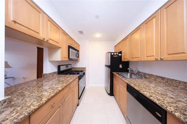 a large kitchen with stainless steel appliances granite countertop a stove a sink and a microwave