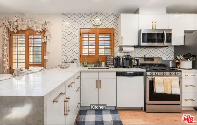 a kitchen with stainless steel appliances granite countertop a stove a sink and a microwave