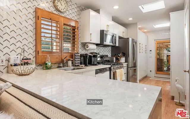a kitchen with stainless steel appliances granite countertop a sink a stove and a refrigerator