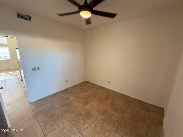 an empty room with a ceiling fan and carpet