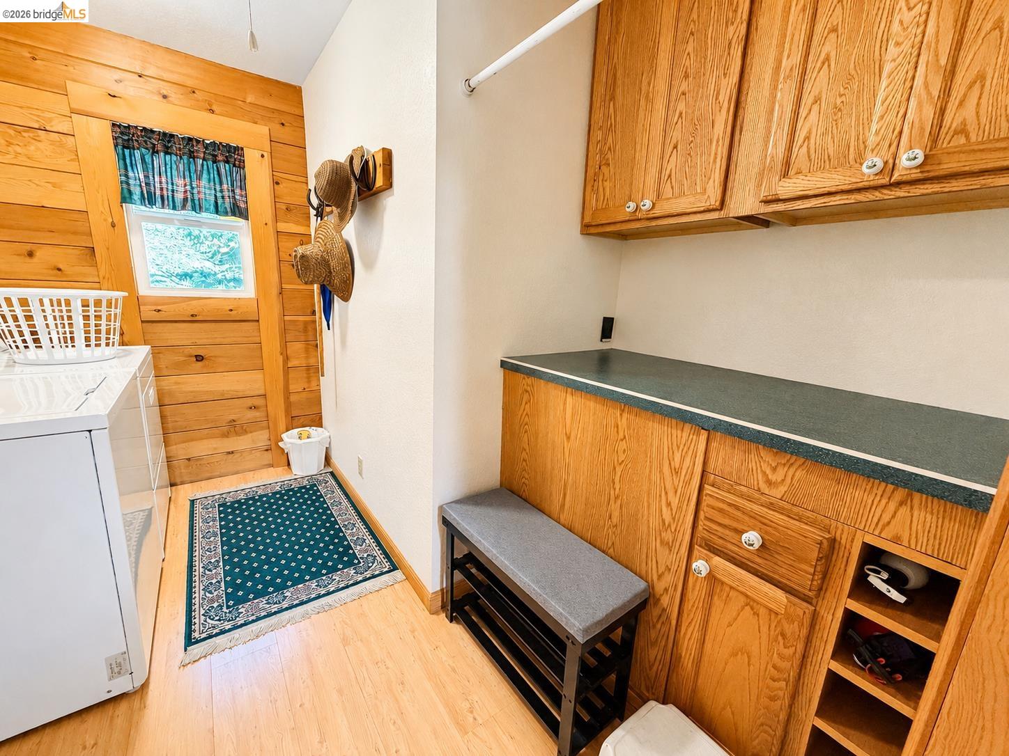 21181 Phoenix Lake Road Sonora, CA 95370 - Photo 22 of 34 Functional utility room featuring wood-finish flooring, natural wood paneling, and a built-in countertop with overhead cabinetry