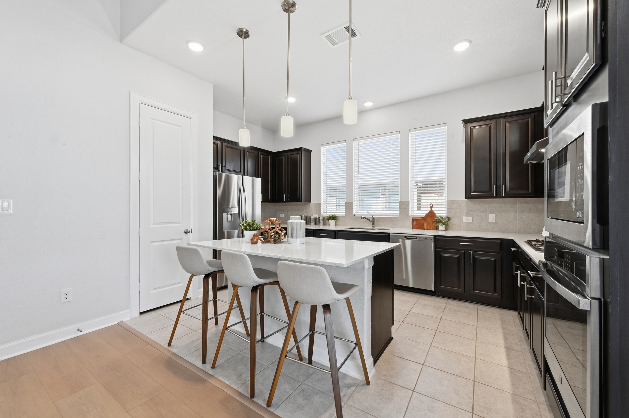 176 Wild Pecan Loop Buda, TX 78610 - Photo 11 of 30 Kitchen featuring a breakfast bar area, a center island, stainless steel appliances, light tile patterned flooring, and light stone counters