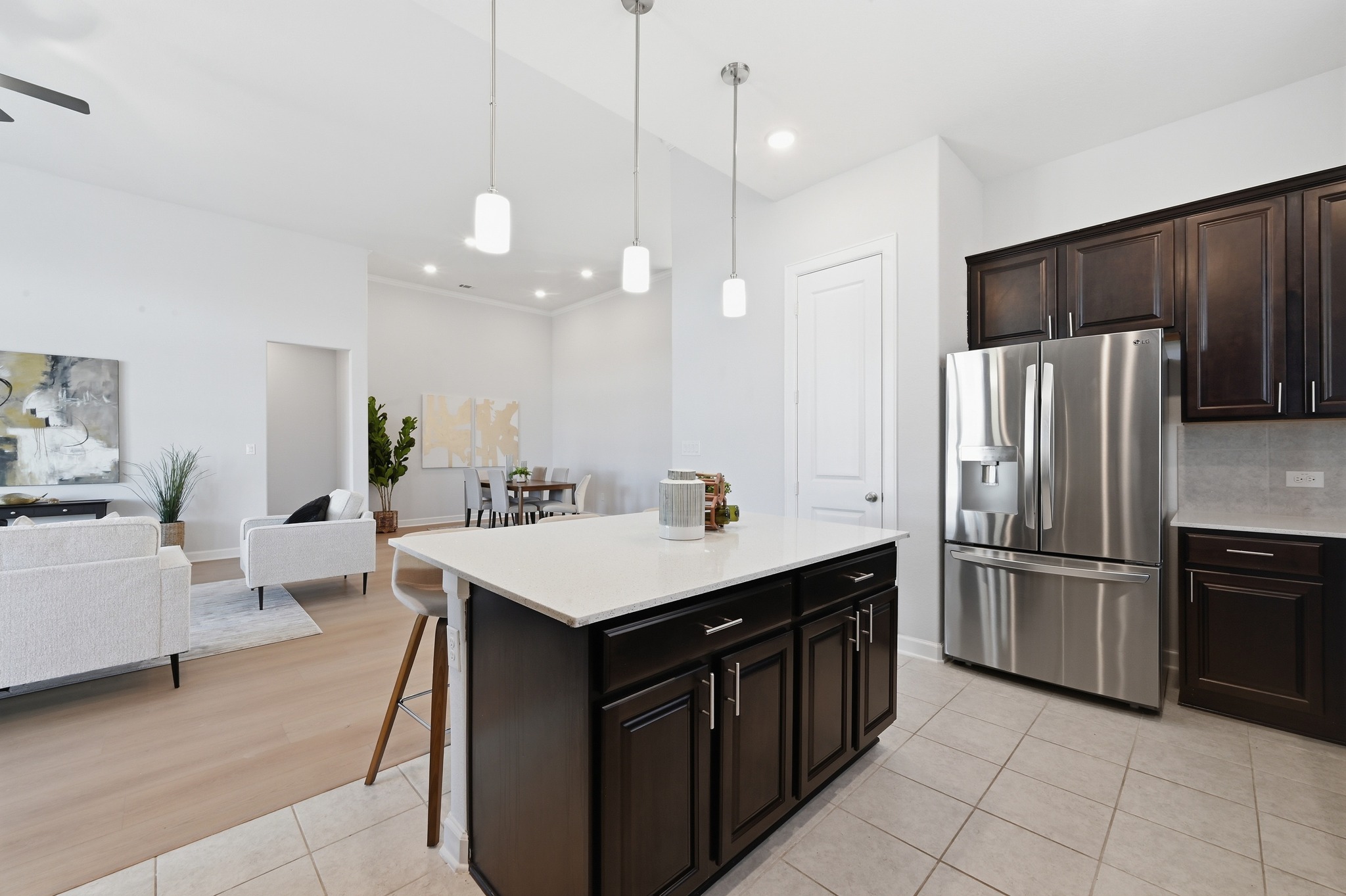 176 Wild Pecan Loop Buda, TX 78610 - Photo 29 of 30 Kitchen featuring stainless steel refrigerator with ice dispenser, open floor plan, dark wood finish cabinets, a center island, and light tile patterned flooring