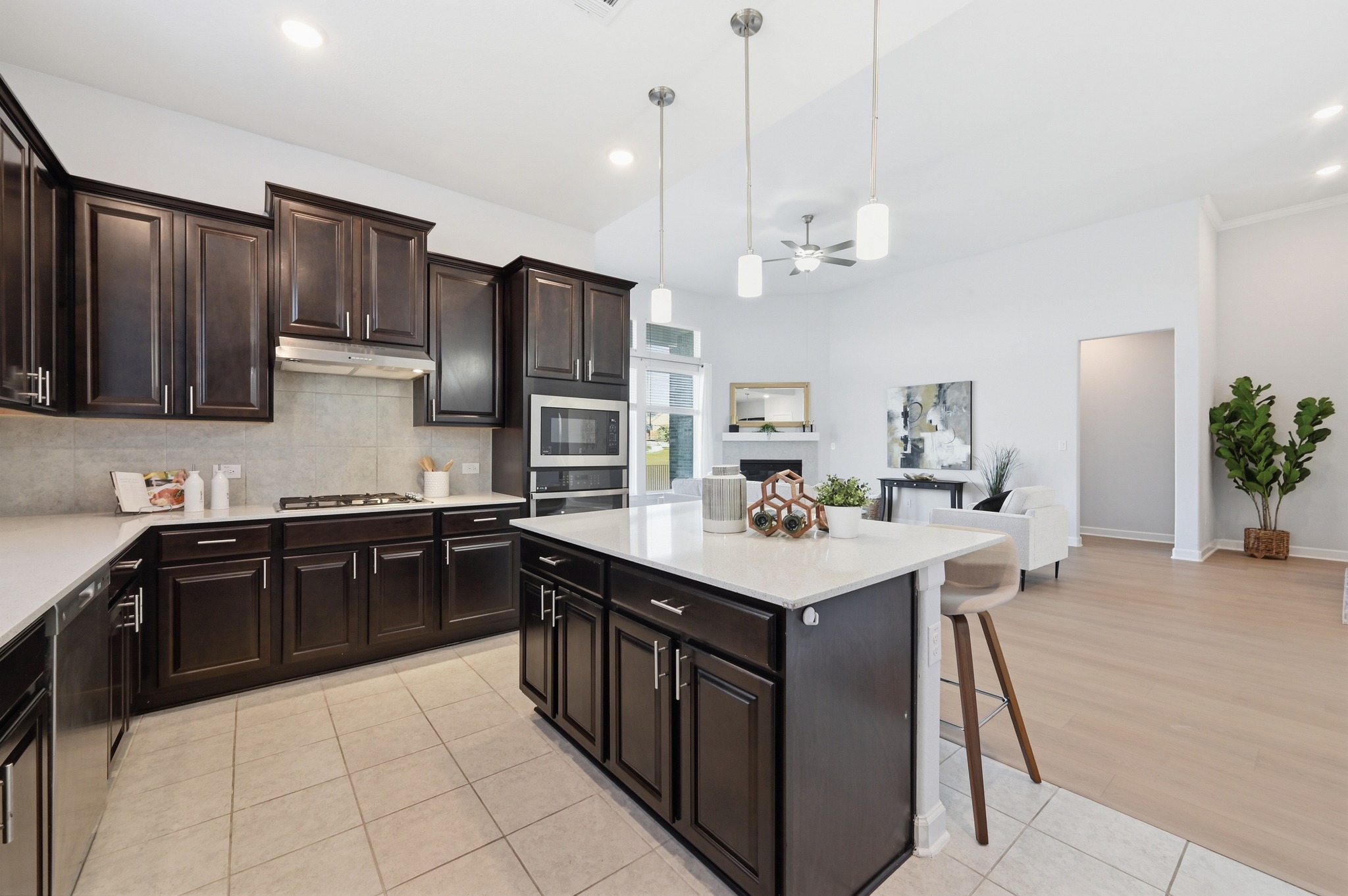 176 Wild Pecan Loop Buda, TX 78610 - Photo 30 of 30 Kitchen featuring a kitchen island, ceiling fan, open floor plan, light tile patterned floors, and dark wood finish cabinetry