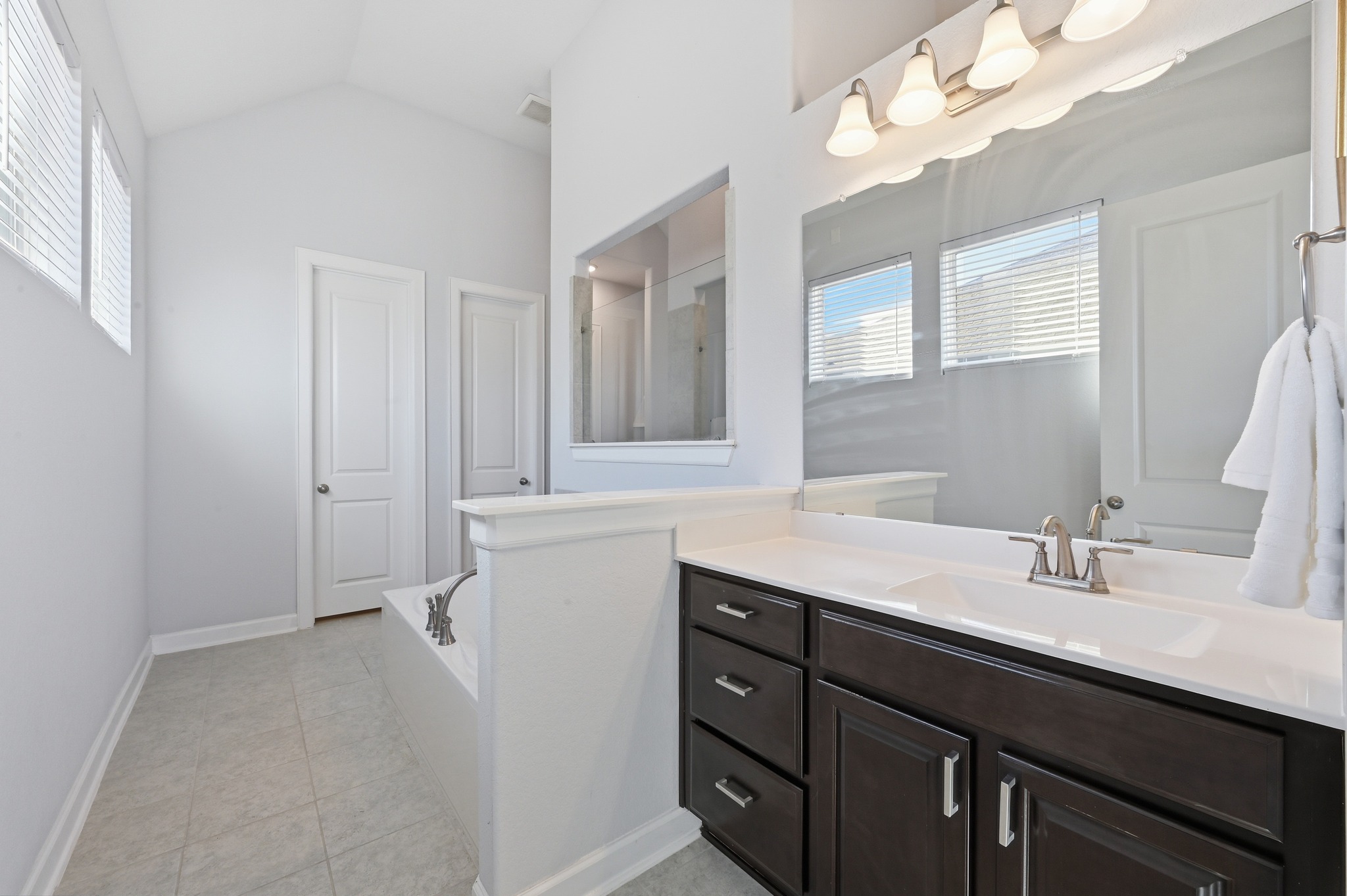 176 Wild Pecan Loop Buda, TX 78610 - Photo 15 of 30 Full bathroom with vanity, a bath, vaulted ceiling, and light tile patterned floors