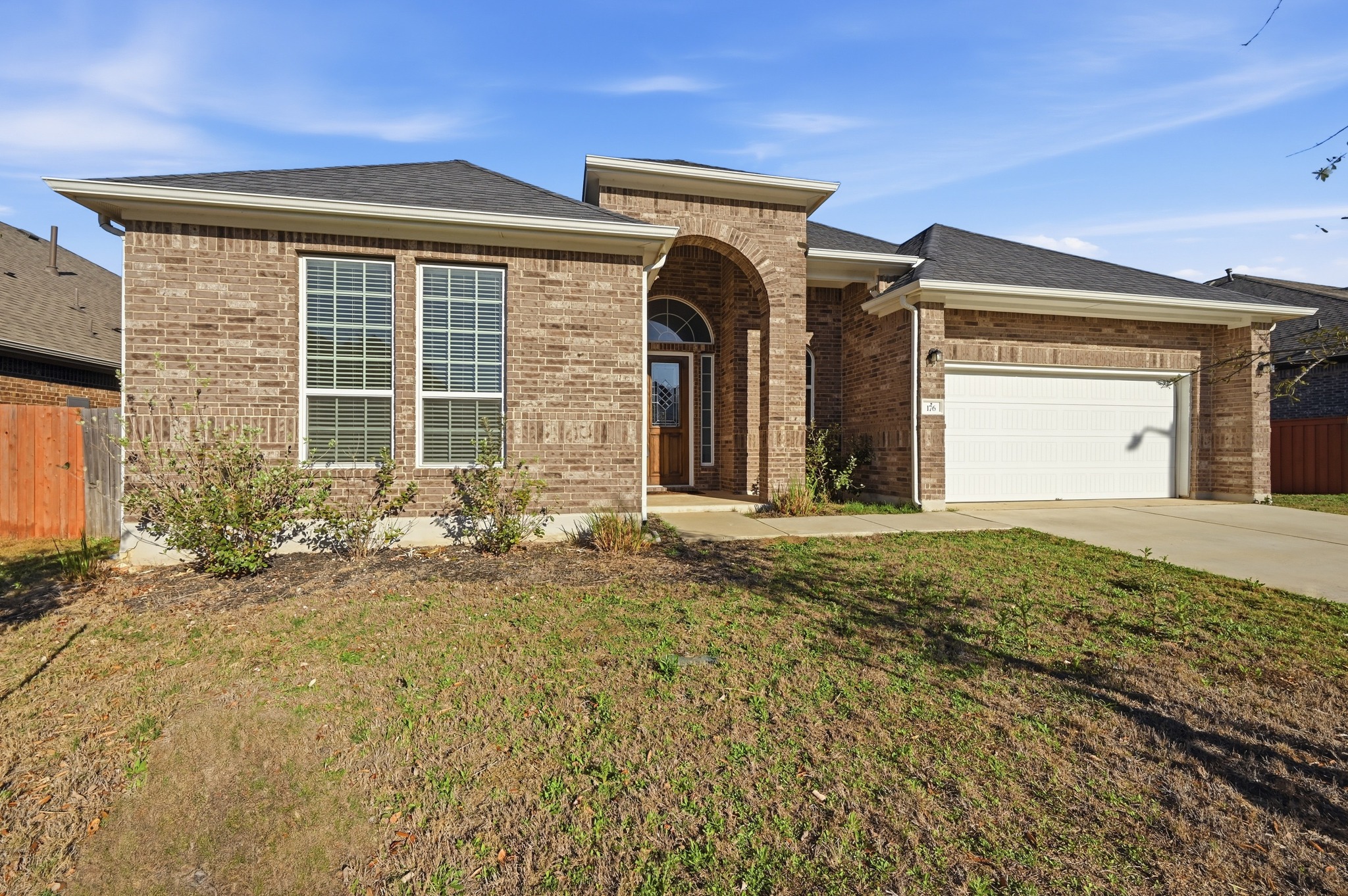 176 Wild Pecan Loop Buda, TX 78610 - Photo 24 of 30 View of front of property with a garage, brick siding, driveway, and a shingled roof