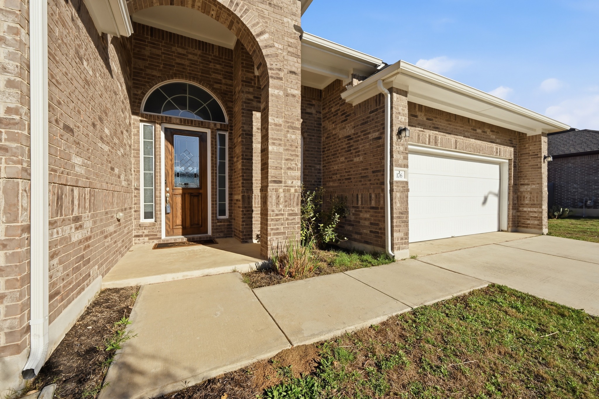 176 Wild Pecan Loop Buda, TX 78610 - Photo 25 of 30 Property entrance with brick siding, an attached garage, a porch, and driveway