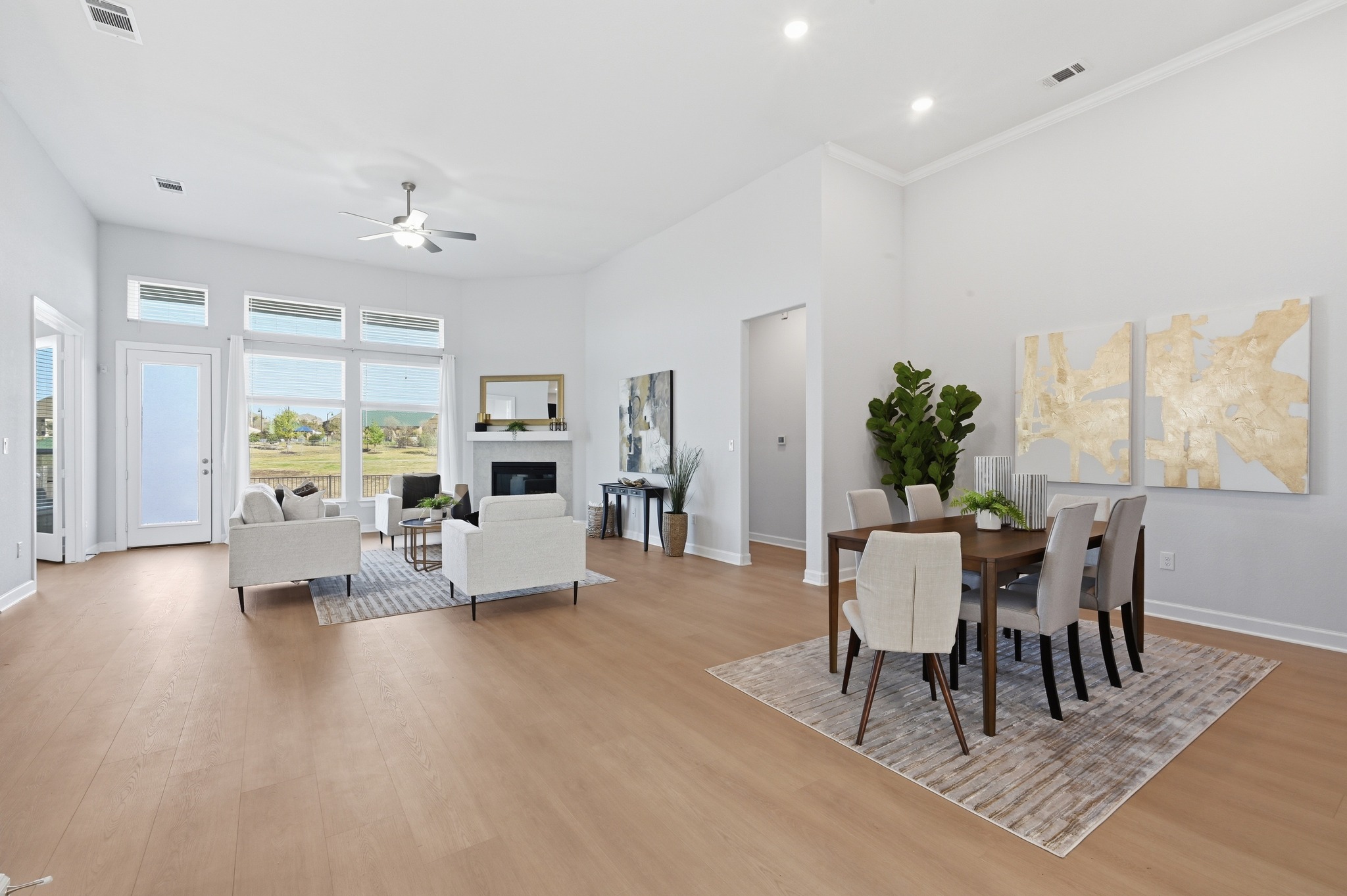 176 Wild Pecan Loop Buda, TX 78610 - Photo 3 of 30 Dining room featuring ceiling fan, light wood-type flooring, a glass covered fireplace, and a high ceiling