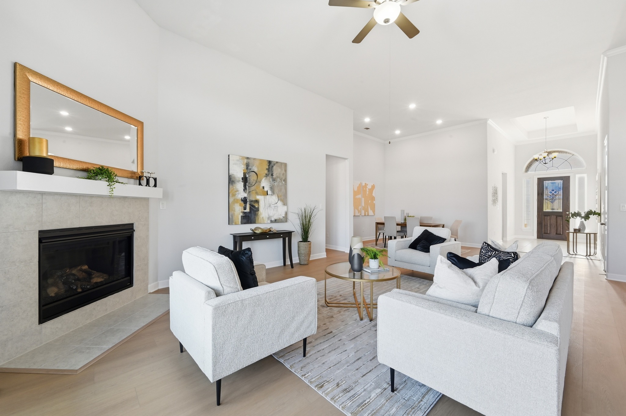 176 Wild Pecan Loop Buda, TX 78610 - Photo 5 of 30 Living room with light wood-type flooring, ceiling fan, a tile fireplace, a high ceiling, and hanging lights