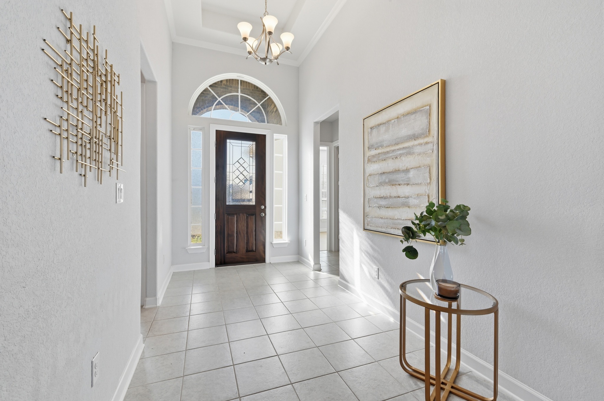 176 Wild Pecan Loop Buda, TX 78610 - Photo 6 of 30 Entryway with a textured wall, hanging lights, light tile patterned floors, and a high ceiling