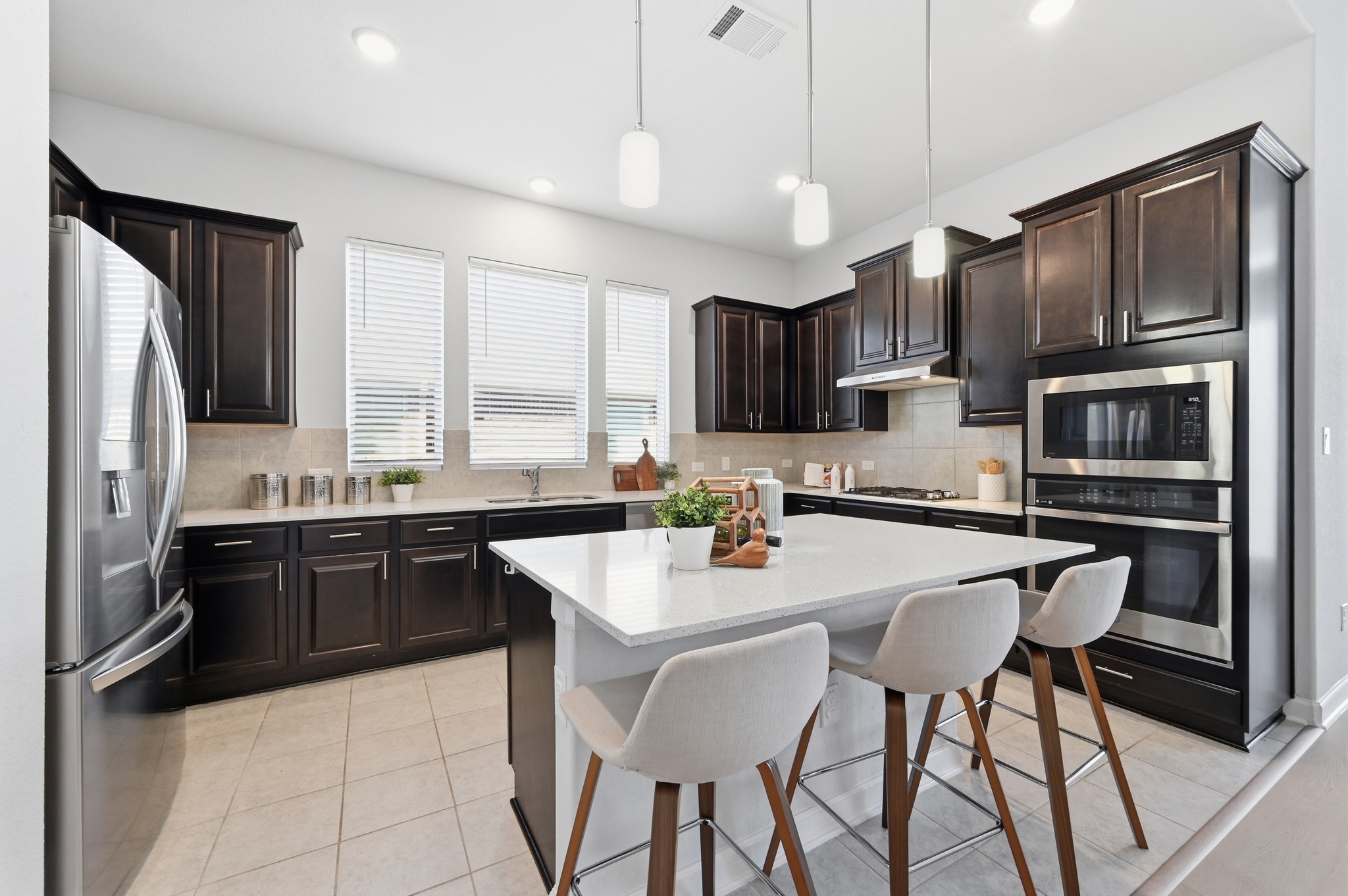 176 Wild Pecan Loop Buda, TX 78610 - Photo 10 of 30 Kitchen with a breakfast bar, stainless steel appliances, light stone countertops, light tile patterned flooring, and hanging light fixtures
