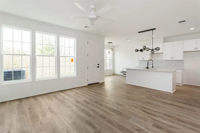 a view of a kitchen with kitchen island a sink wooden floor and a large window