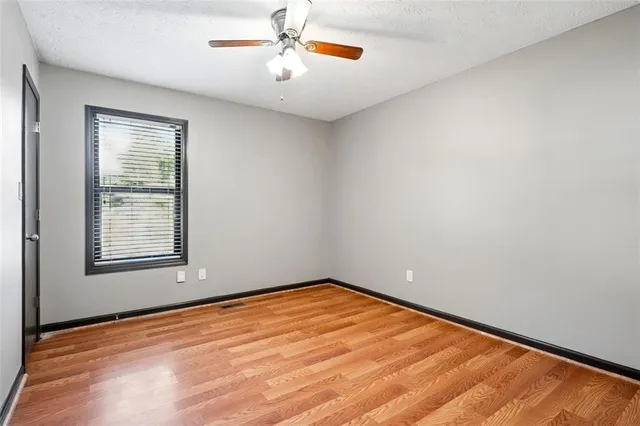 an empty room with a window and ceiling fan