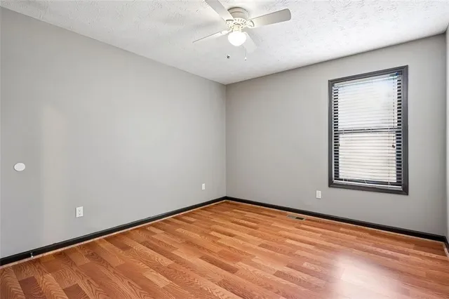 an empty room with a window and ceiling fan