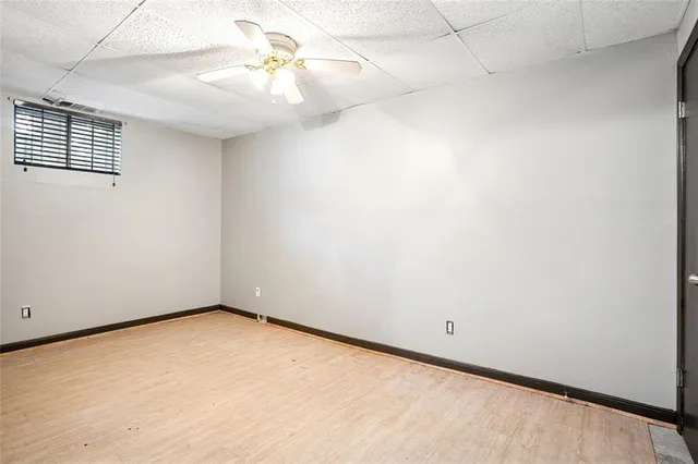 an empty room with a chandelier fan and windows