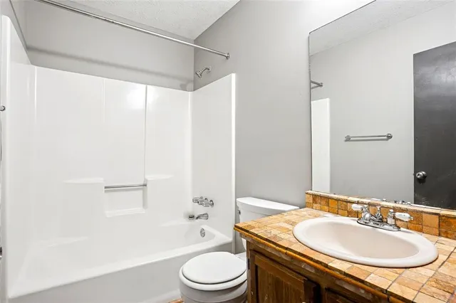 a bathroom with a granite countertop sink toilet a mirror and shower